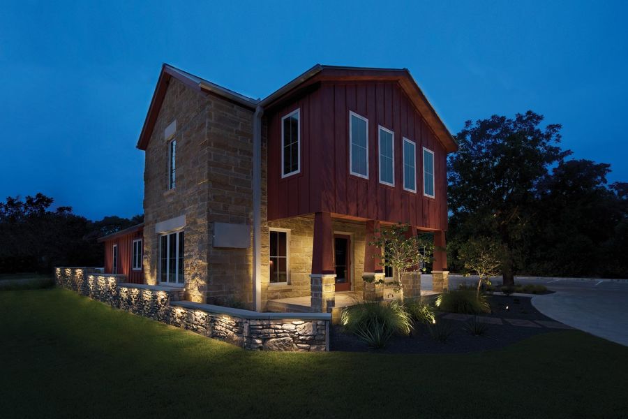 Red and stone house with warm wall lighting accenting the exterior