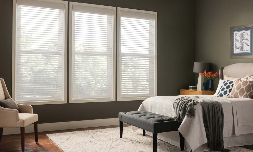 Bright bedroom featuring Lutron horizontal sheer shades, a stylish bed, and a comfortable chair.