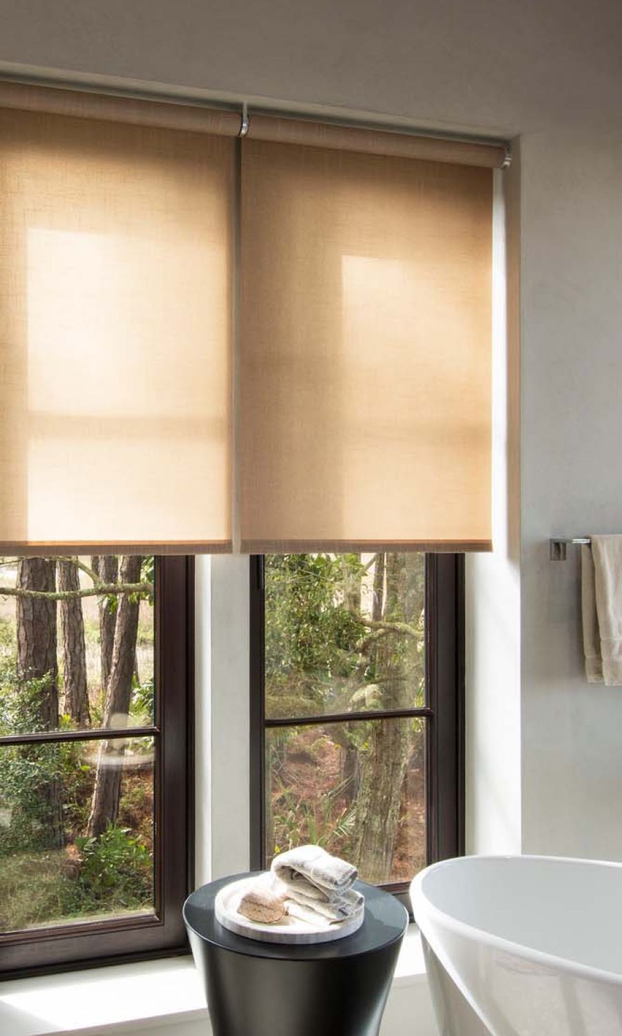 bathroom with neutral savant shades hanging and warm lighting